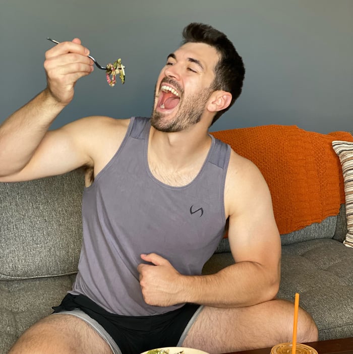 Coach is posing with a big smile wearing sleeveless gray undershirt.